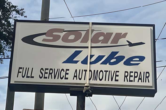 Outdoor sign reads "Solar Lube Full Service Automotive Repair" with a swoosh graphic and letters in brown and blue.