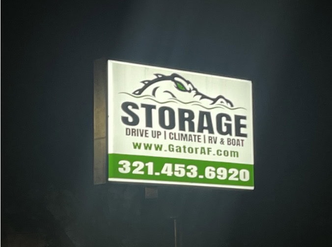 Illuminated sign for Gator Storage, featuring an alligator icon, website, and phone number 321-453-6920.